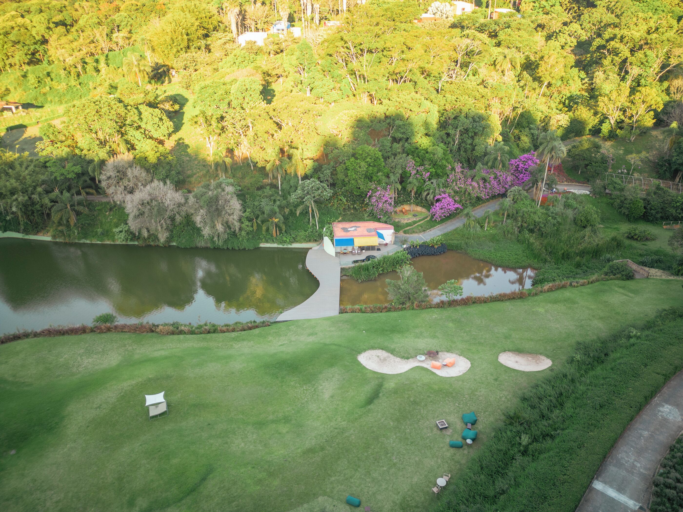 An aerial view of a golf course with a clubhouse, ponds, and green areas.