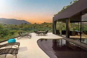 A modern outdoor terrace with a pool, seating, and a view of a mountainous landscape. - Hotel Unique Garden (Mairipora)