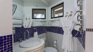 Casa de banho com lavatório, sanita e porta-toalhas.