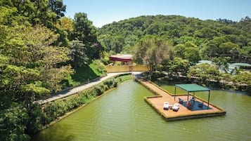A riverside hotel with a floating deck, a pathway, and lush greenery.