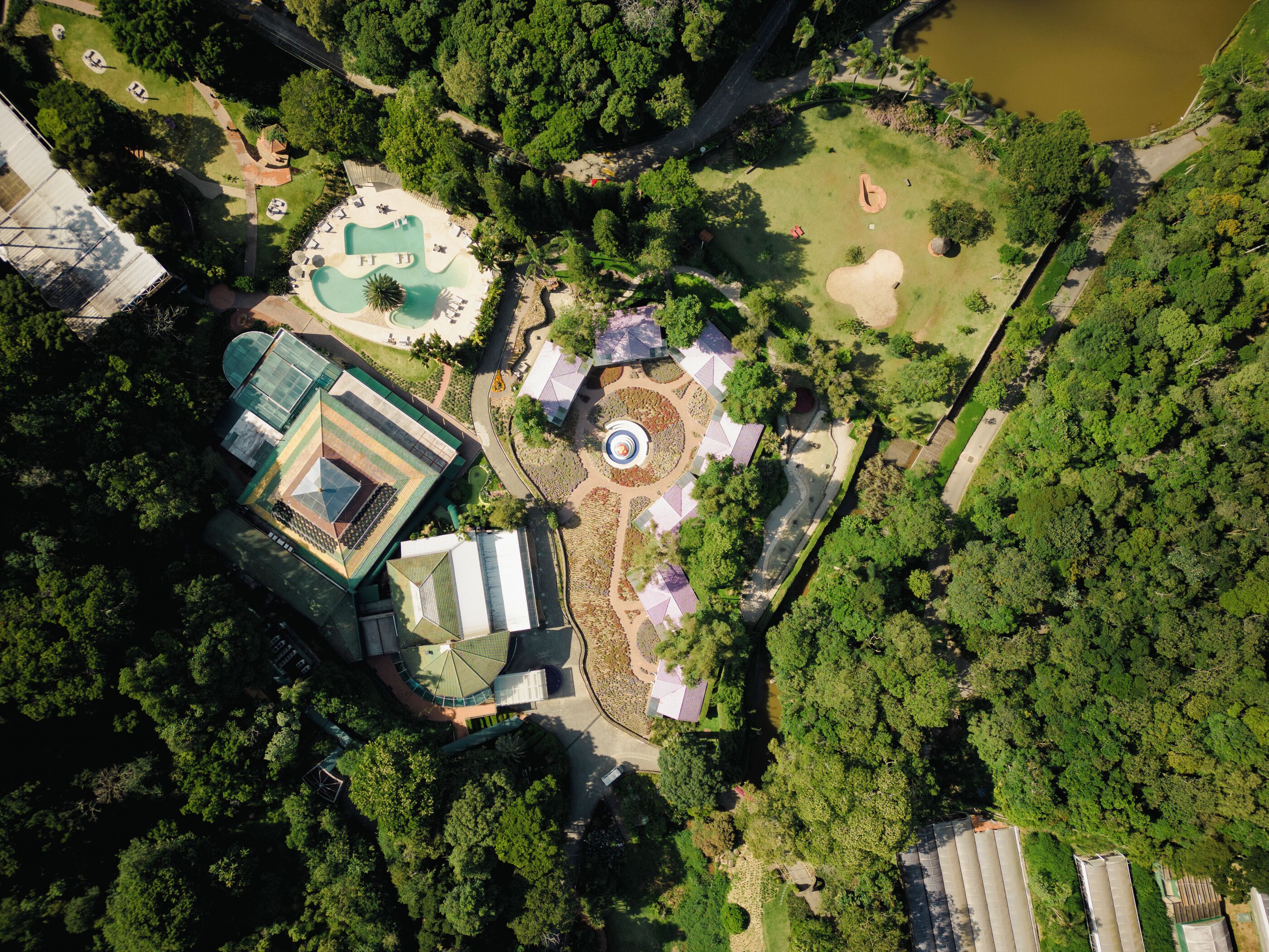 An aerial view of a resort with a swimming pool, tennis courts, and a landscaped garden.