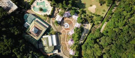 An aerial view of a resort with a swimming pool, tennis courts, and a landscaped garden.