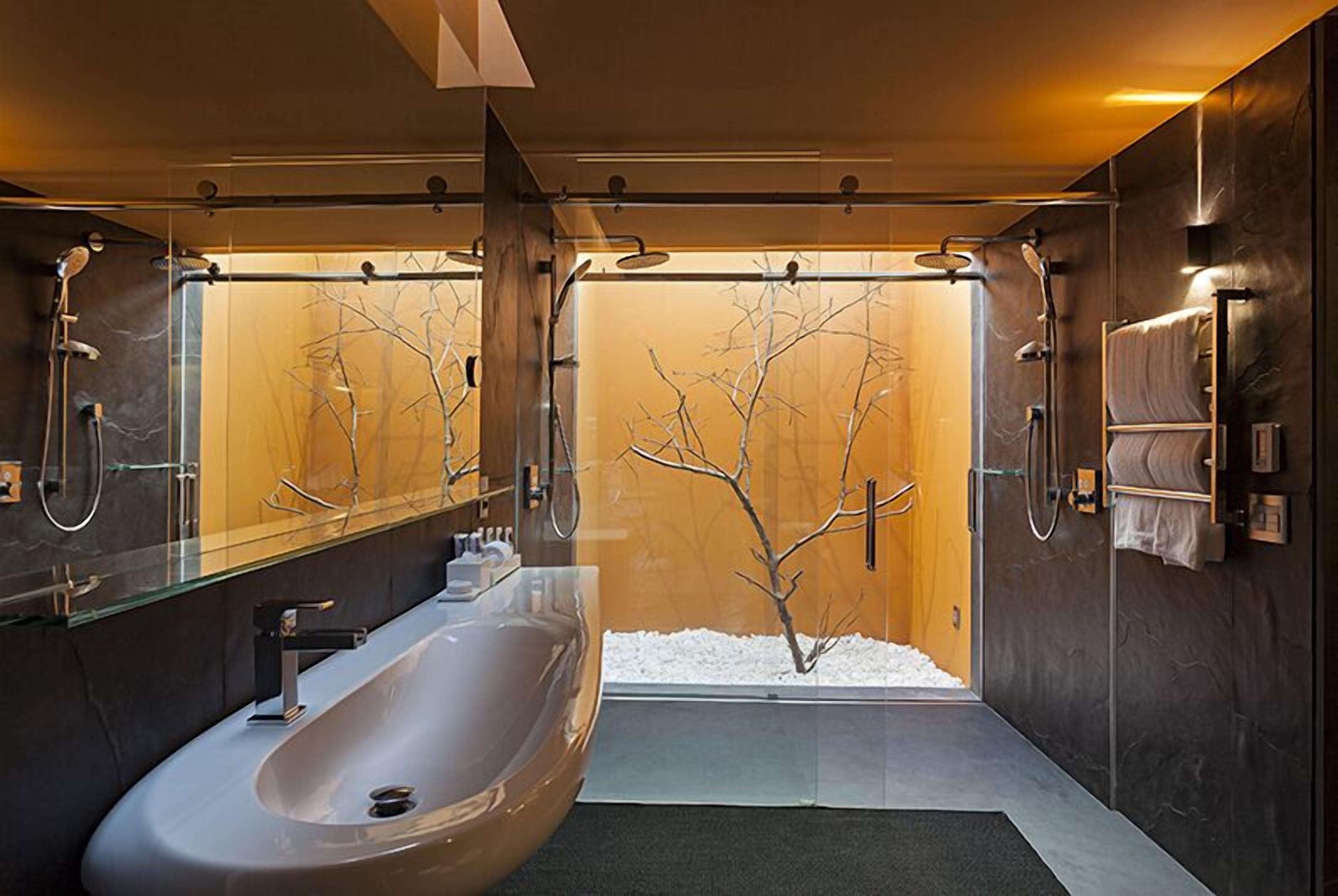 A modern bathroom with a large bathtub, a glass shower enclosure, and a wooden wall with a tree design.