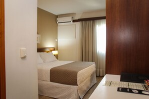 A hotel room with a bed, bedside table, lamp, air conditioning unit, and curtains. - Bristol Centro Cívico Multy Hotel (Curitiba)