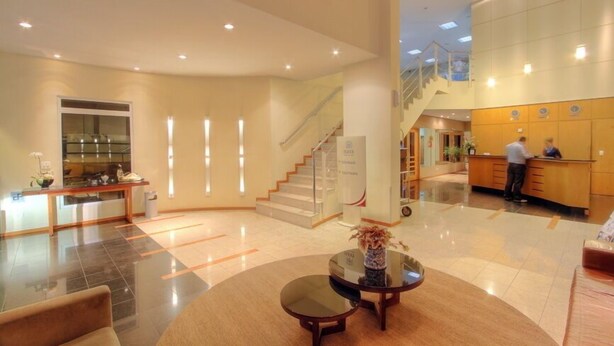 Un vestíbulo de hotel con una recepción, una escalera y un comedor.