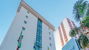 El exterior del edificio Bristol Central con varias banderas, incluyendo la bandera brasileña, y un letrero que anuncia el restaurante Casa Bertelli.