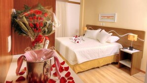 Una habitación de hotel con una cama, una mesita de noche, una lámpara y un ramo de flores.