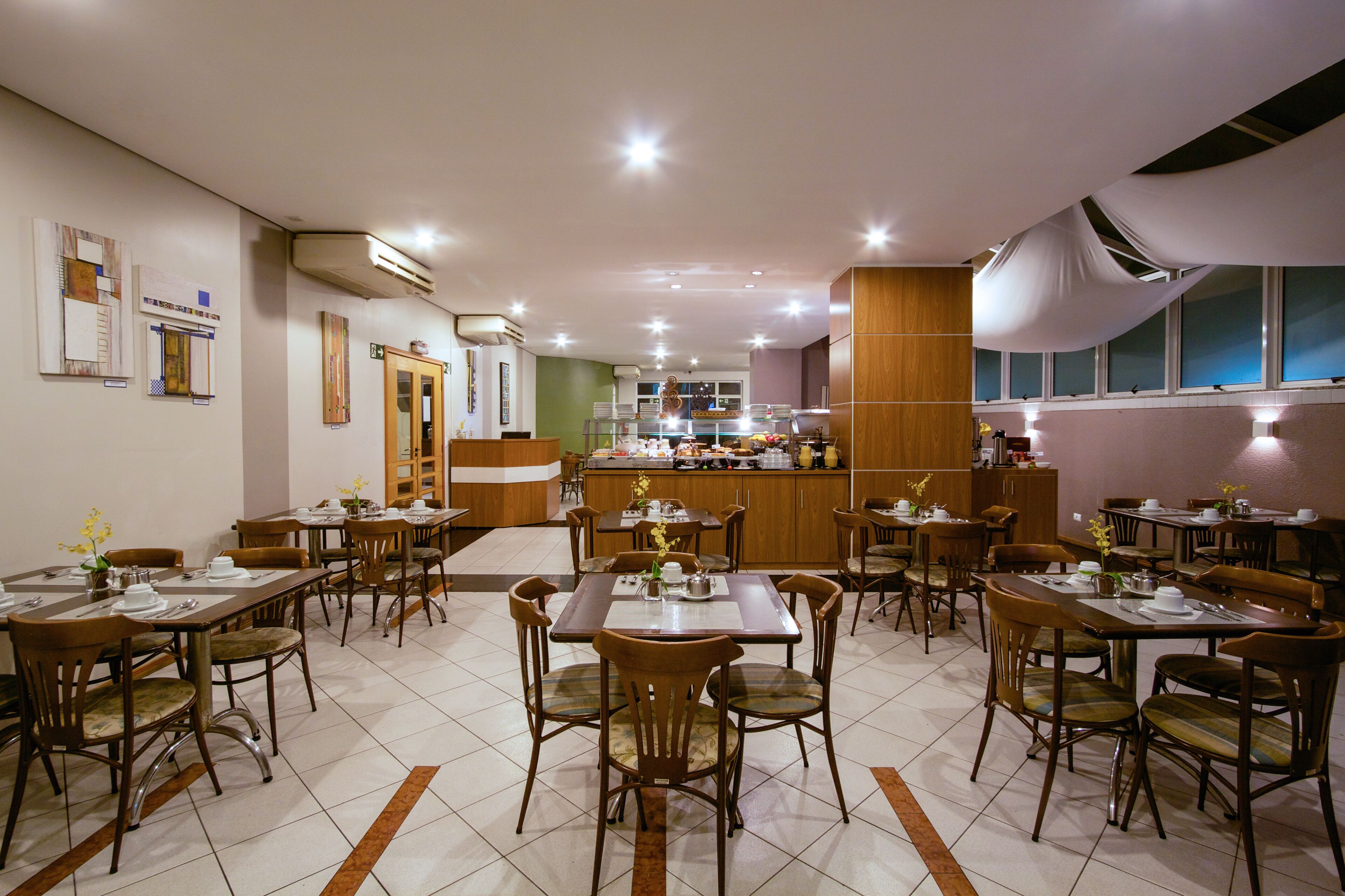 A restaurant with multiple dining tables and chairs, a kitchen area, and a bar.