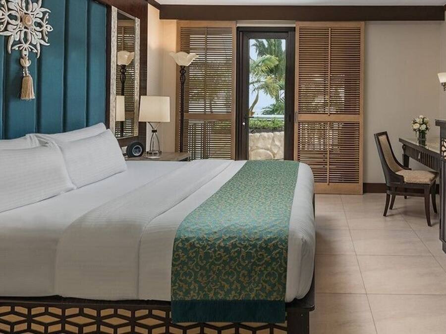 Een hotelkamer met een bed, een bureau met telefoon, een televisie en een zithoek met stoelen.