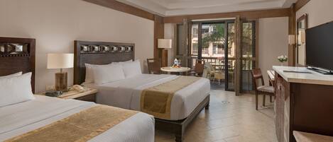 A hotel room with two beds, a desk, a chair, and a TV.