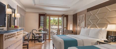 Habitación de hotel con cama, escritorio con teléfono, una silla y una mesa con un jarrón de flores.