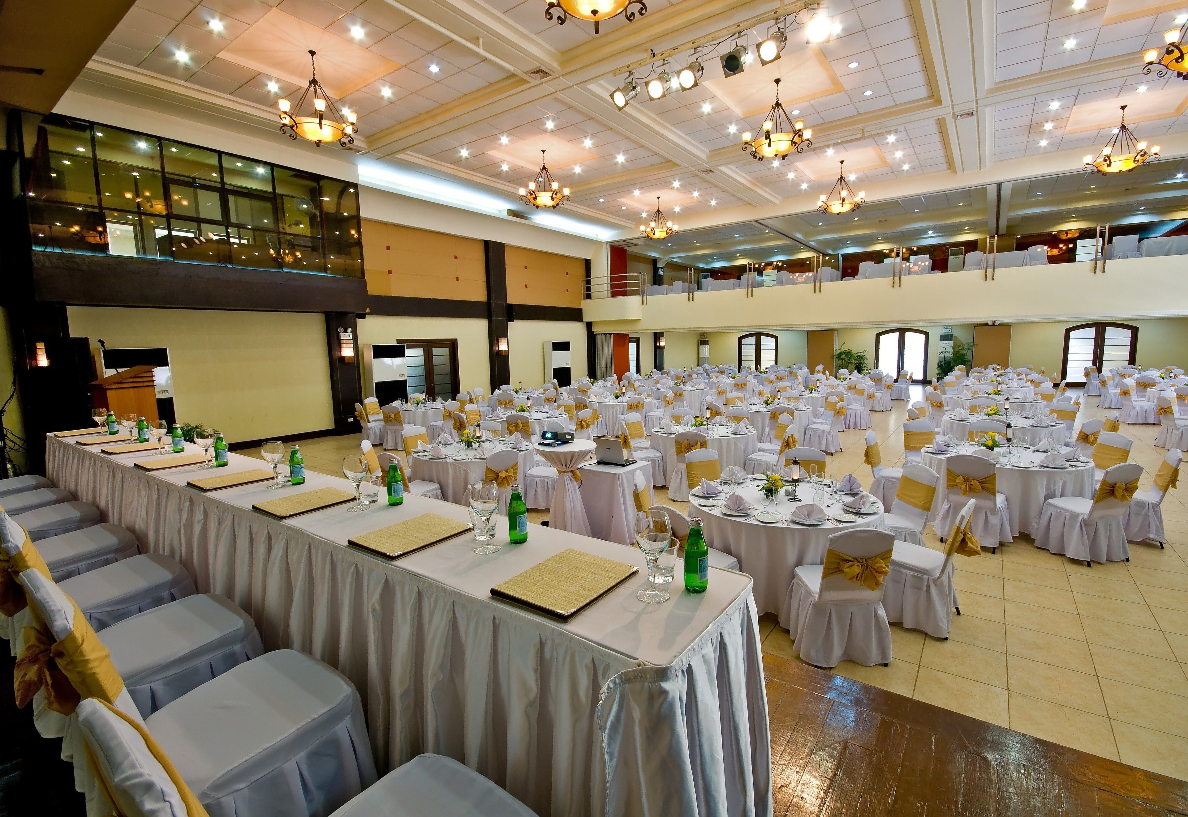 A banquet hall with tiered seating, chandeliers, and tables set for a formal event.