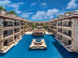 Un hotel con piscina central, varios balcones y zonas de estar al aire libre.