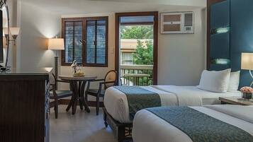A hotel room with two beds, a desk, a chair, a TV, and a balcony with a view.