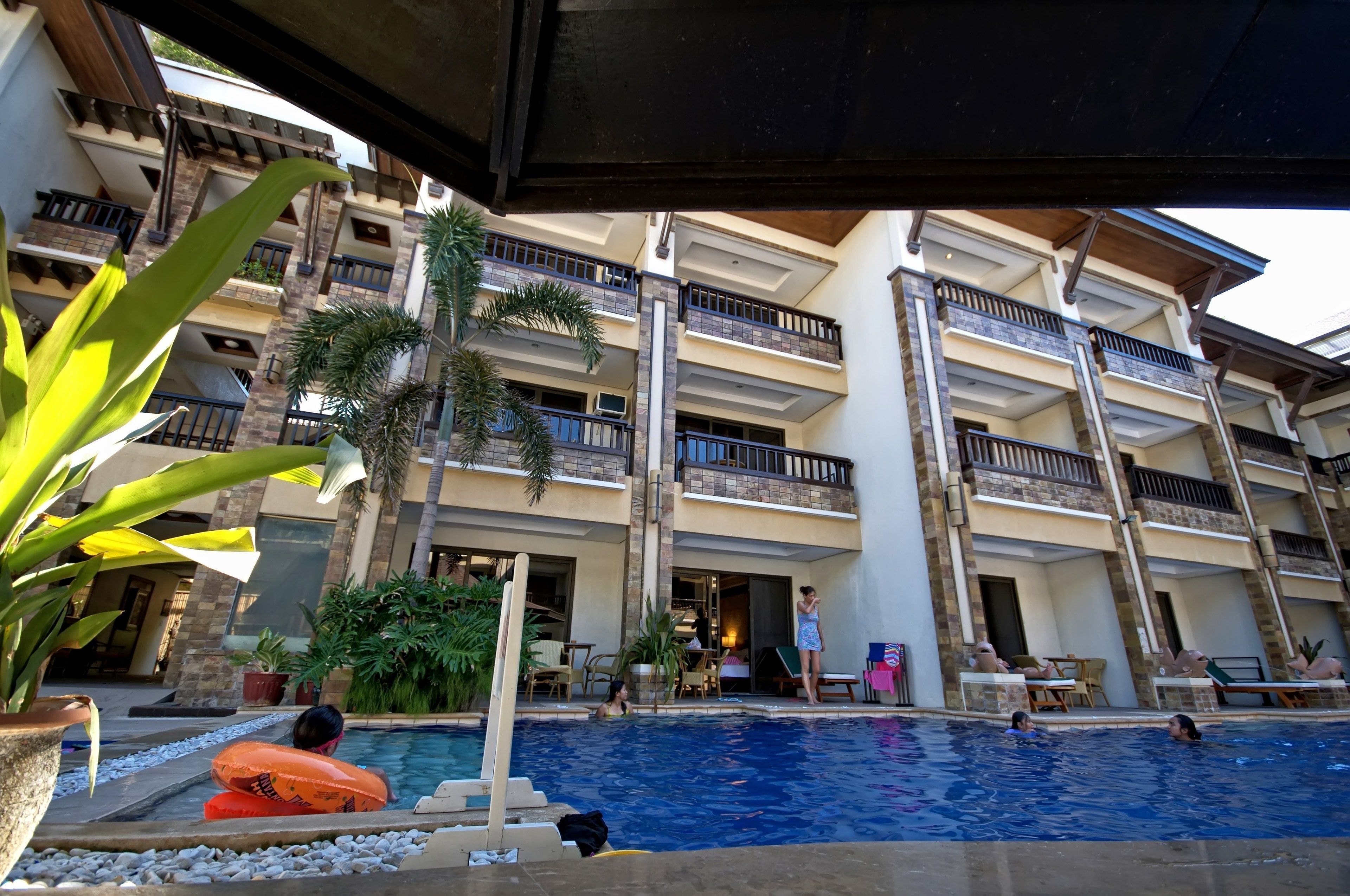 A multi-story hotel with a swimming pool, outdoor seating, and balconies.