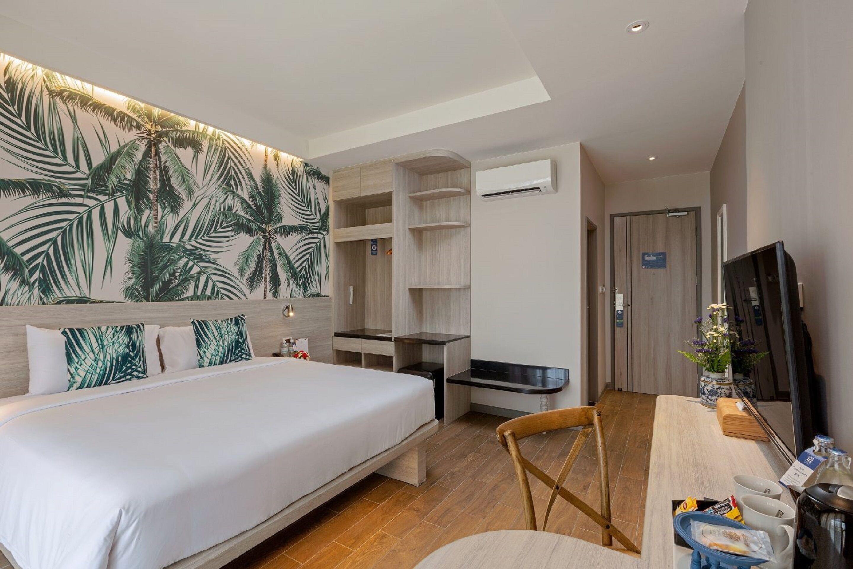 Una habitación de hotel con una cama, un escritorio con una silla, un televisor y una estantería en la pared.