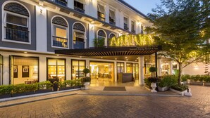 A hotel entrance with a covered patio, large windows, and a well-lit facade. - Sawaddi Patong Resort & Spa by Tolani (Patong)