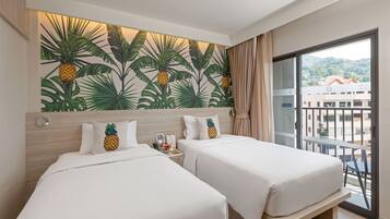 Habitación de hotel con dos camas, un ventanal con vistas a edificios y un mural temático tropical.