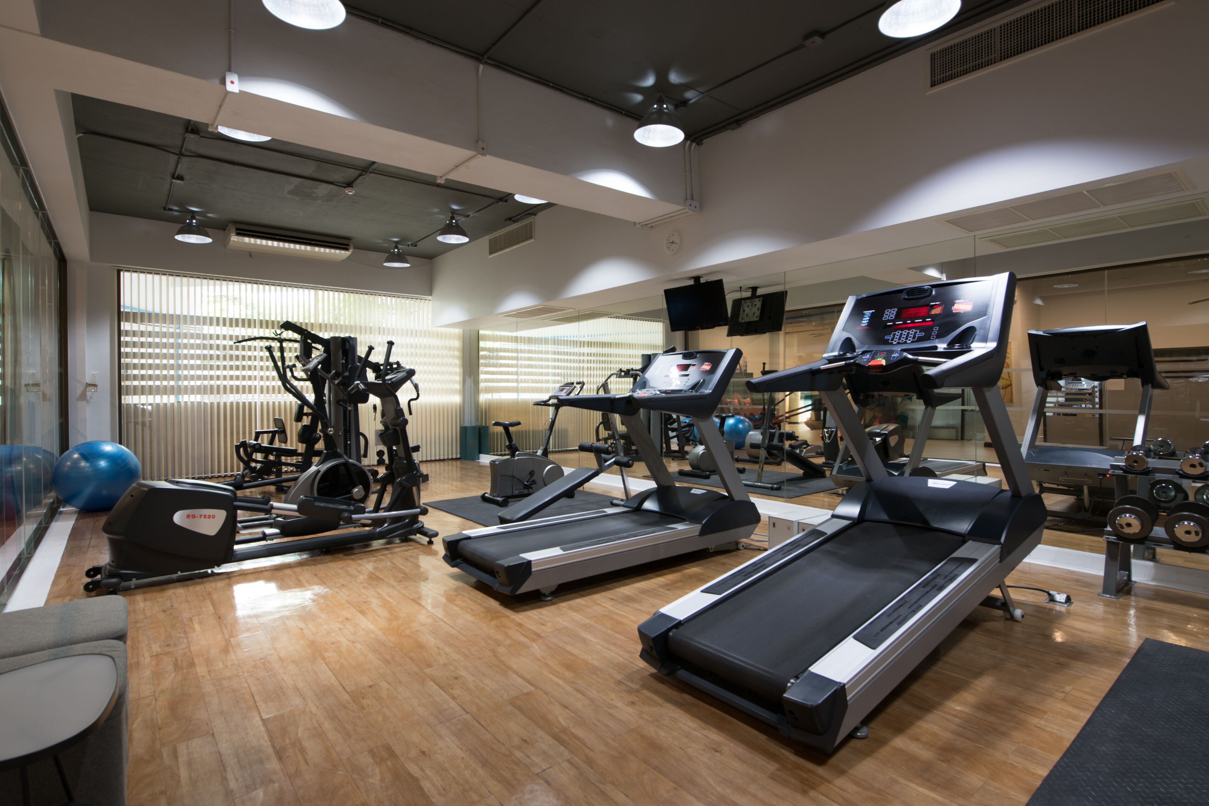 A gym with treadmills, stationary bikes, and exercise balls.