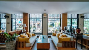 A modern lobby with two sofas, a coffee table, and a large potted plant. - Sawaddi Patong Resort & Spa by Tolani (Patong)