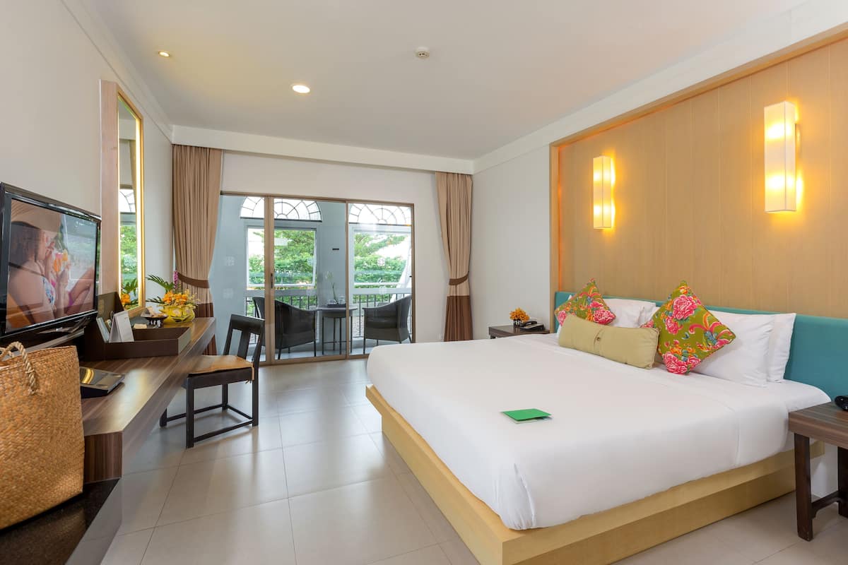 Habitación de hotel con una cama grande, un escritorio con televisor y vistas al exterior.