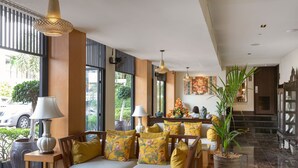 A modern lobby with a sofa set, a large potted plant, and a dining area with a table and chairs. - Sawaddi Patong Resort & Spa by Tolani (Patong)