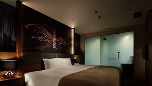 A hotel room with a large bed, a nightstand with a lamp, a wall art piece, and a sliding door closet. - Akasaka Granbell Hotel (Tokyo)