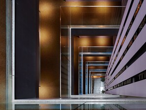 A modern building with a glass facade, a central staircase, and a series of balconies.