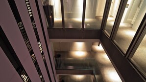 A modern interior with a glass staircase, reflective surfaces, and a minimalist design. - Akasaka Granbell Hotel (Tokyo)