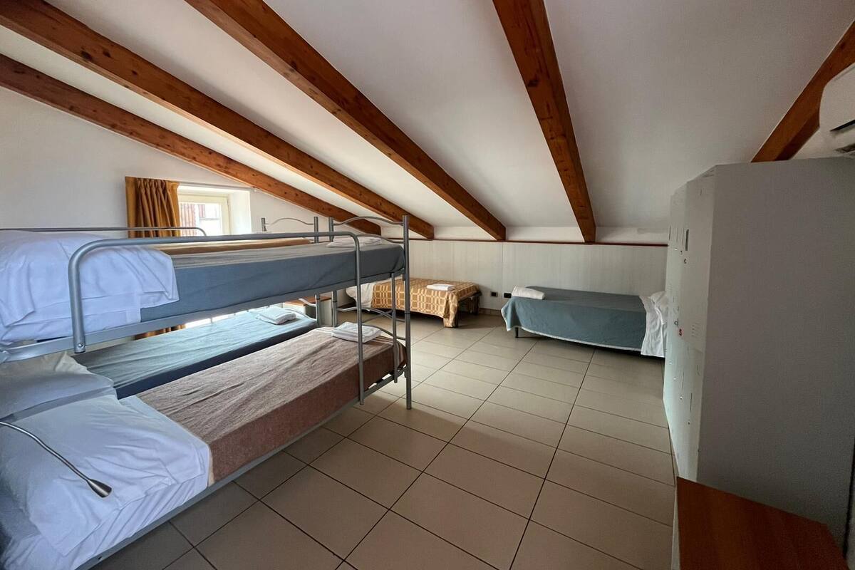 A dormitory room with bunk beds, a small table, and a refrigerator.