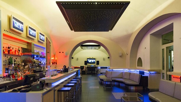 Zona de bar con mostrador, taburetes y un espacio de estar con sofás.