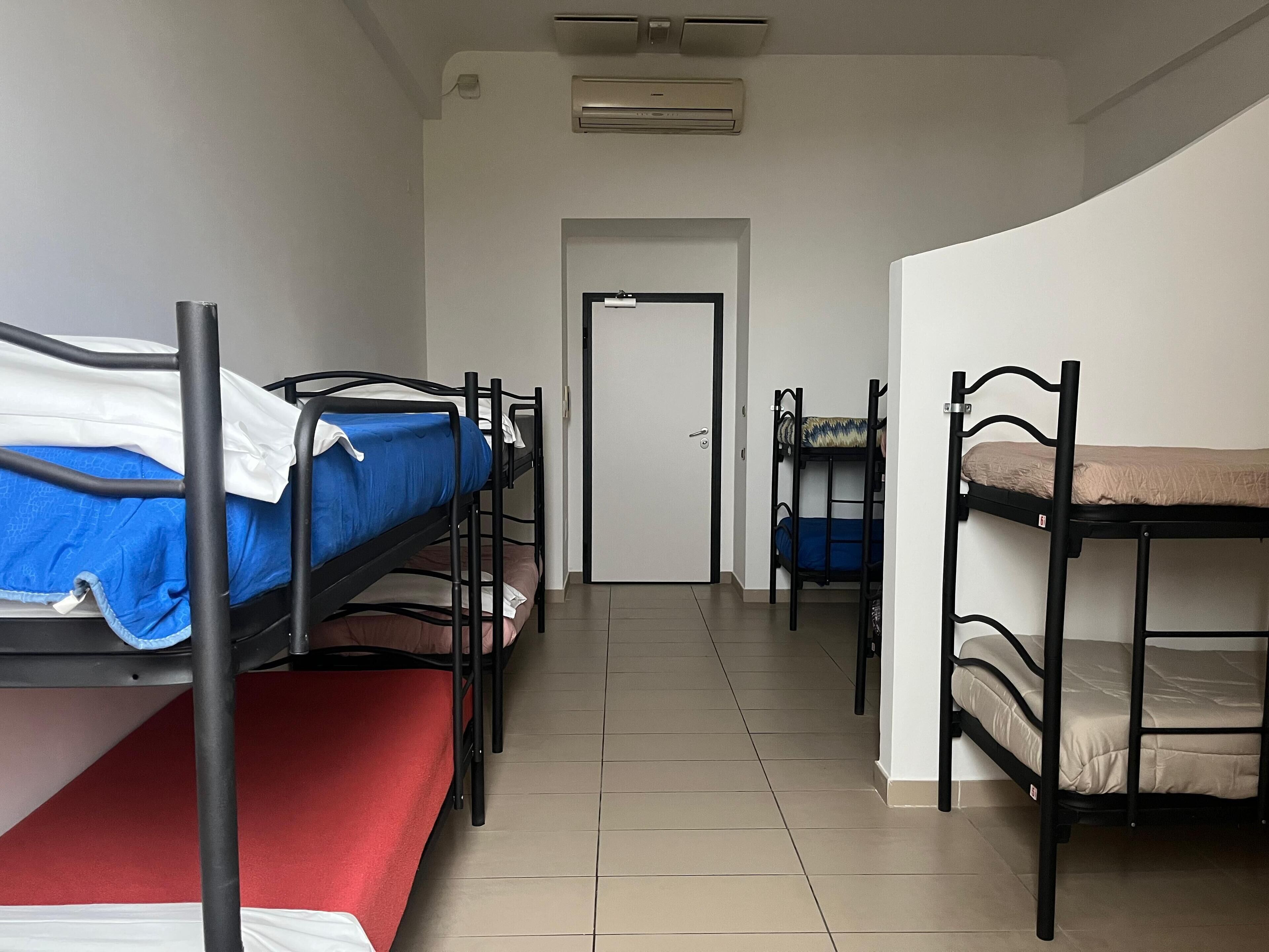 A corridor with bunk beds, a door, and an air conditioning unit.