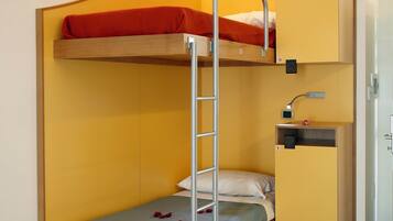 Una cama litera con escritorio y una escalera, un pequeño estante y una puerta.