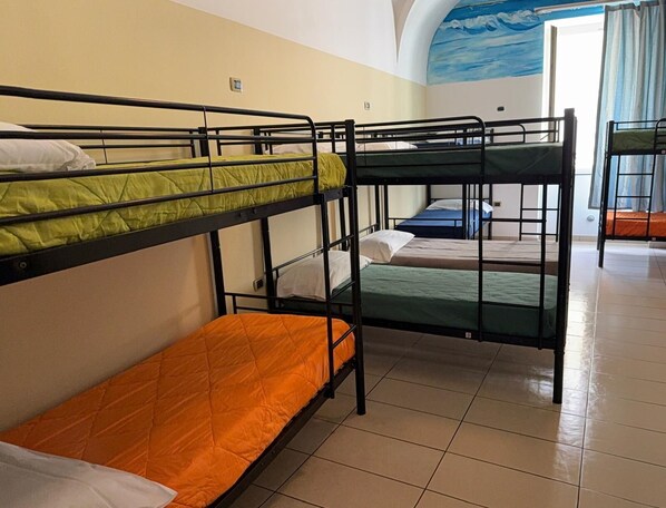 Un dormitorio con literas, piso de baldosas y un mural de nubes en la pared.