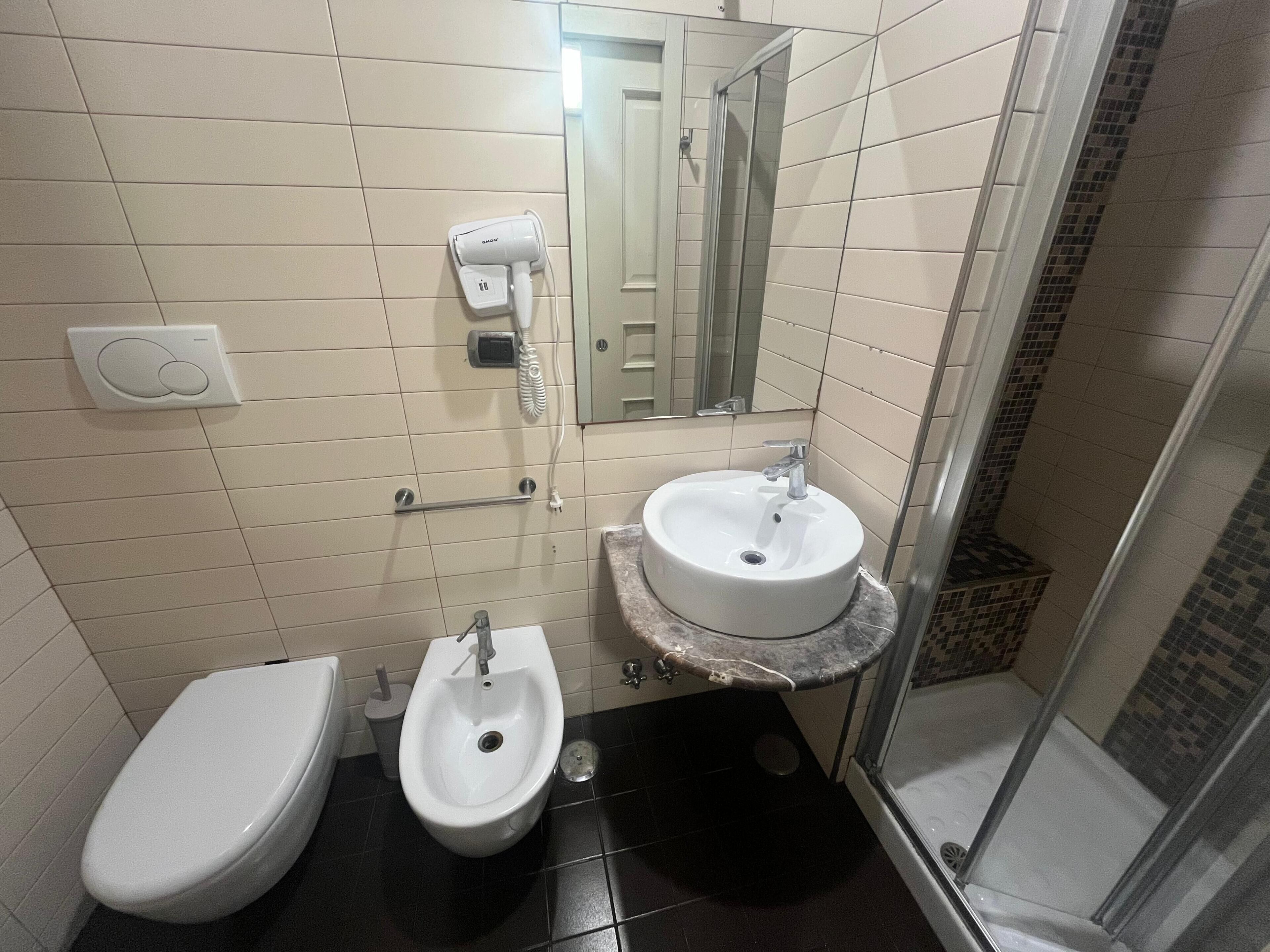 Un baño con inodoro, bidé, lavabo y secador de manos.