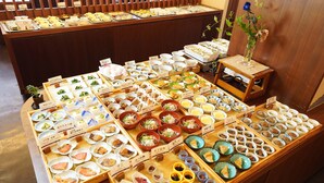 A buffet with various dishes and a small table with a vase of flowers. - Hotel Riverge Akebono (Fukui)
