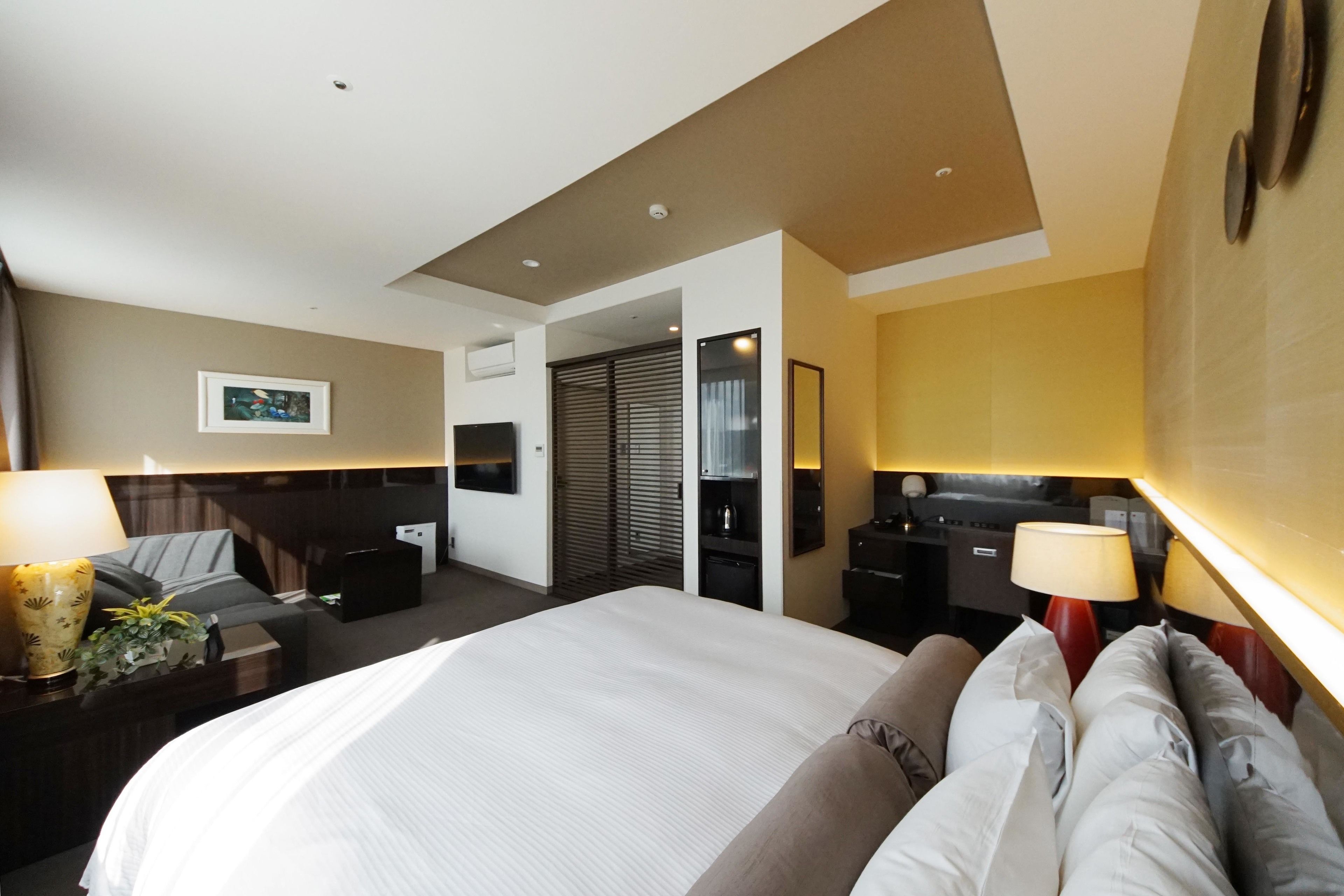A hotel room with a large bed, bedside tables, a desk, and a wardrobe.