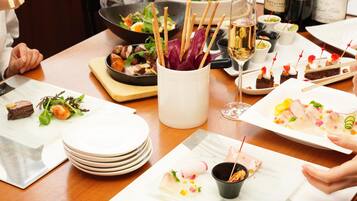 Een eettafel met verschillende gerechten, waaronder een salade, dessert en voorgerechten, samen met wijnflessen en glazen.