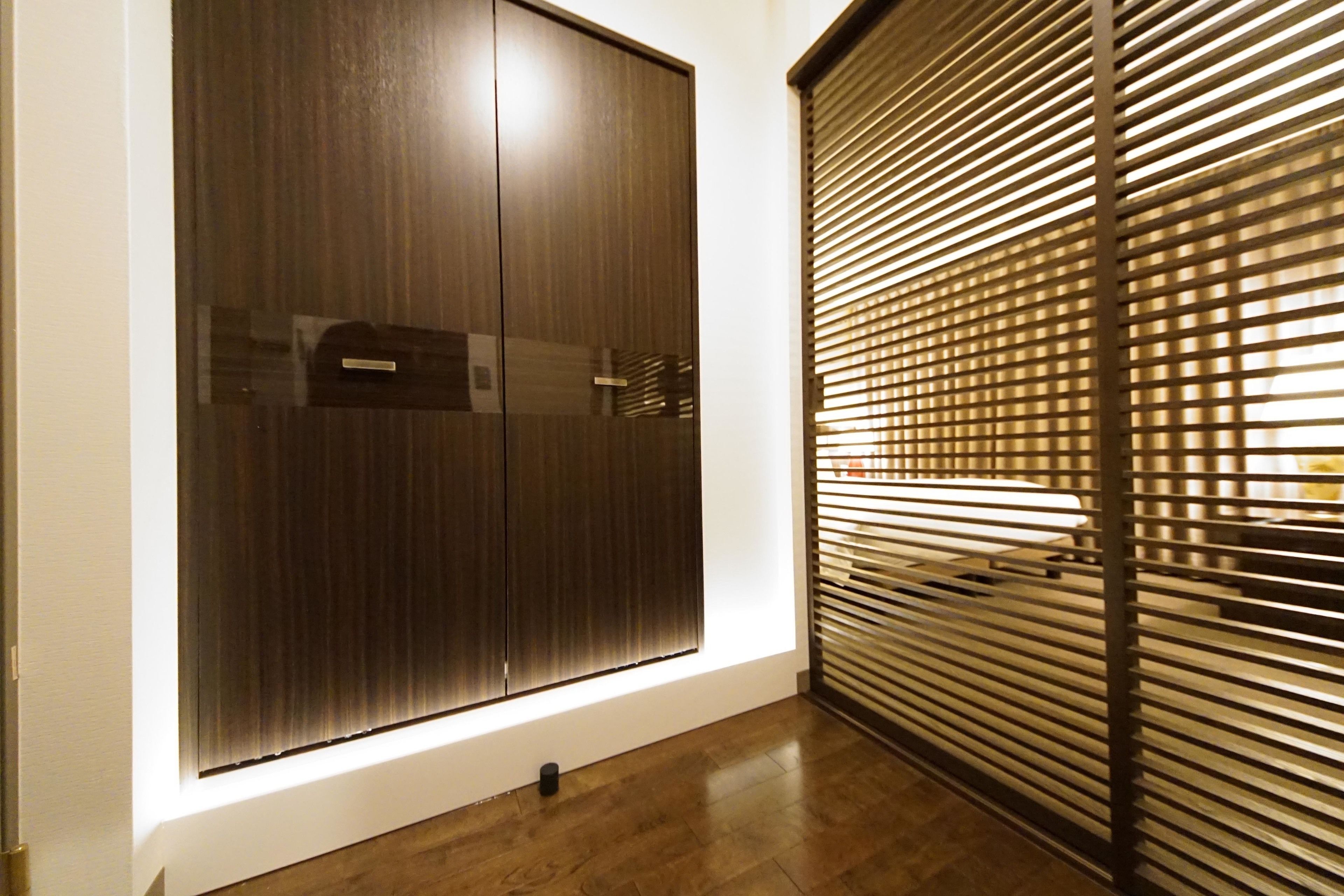 Una habitación con un armario grande, una ventana con persianas y suelo de madera.