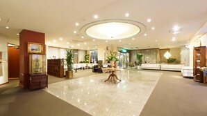 A spacious lobby with a polished floor, a central round table, and seating areas. - Hotel Riverge Akebono (Fukui)