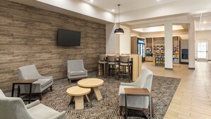Et moderne loungeområde med siddepladser, et fladskærms-tv og kaffestation.