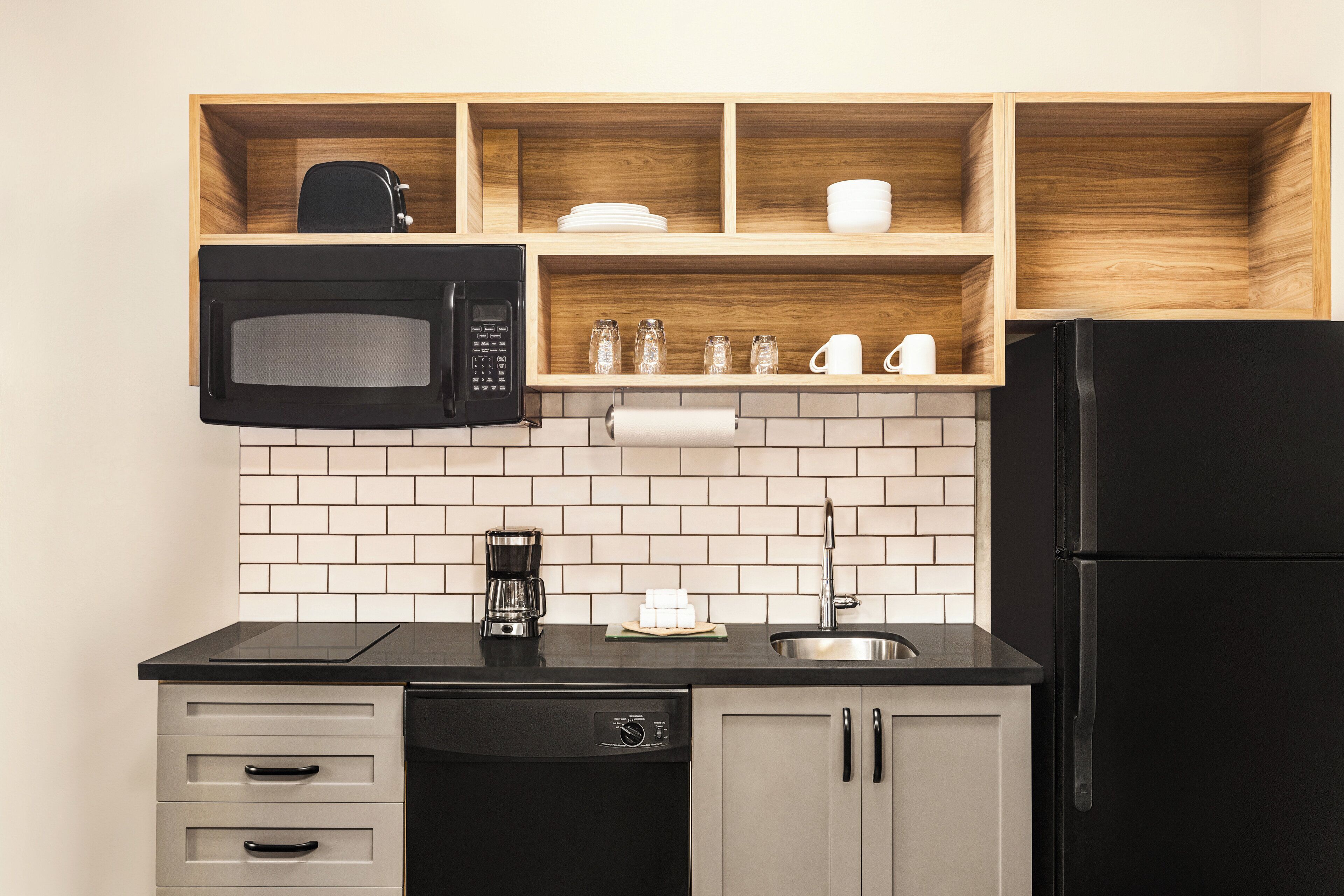 Una cucina con un forno a microonde nero, una macchina da caffè e un frigorifero.