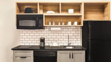 Una cucina con un forno a microonde nero, una macchina da caffè e un frigorifero.