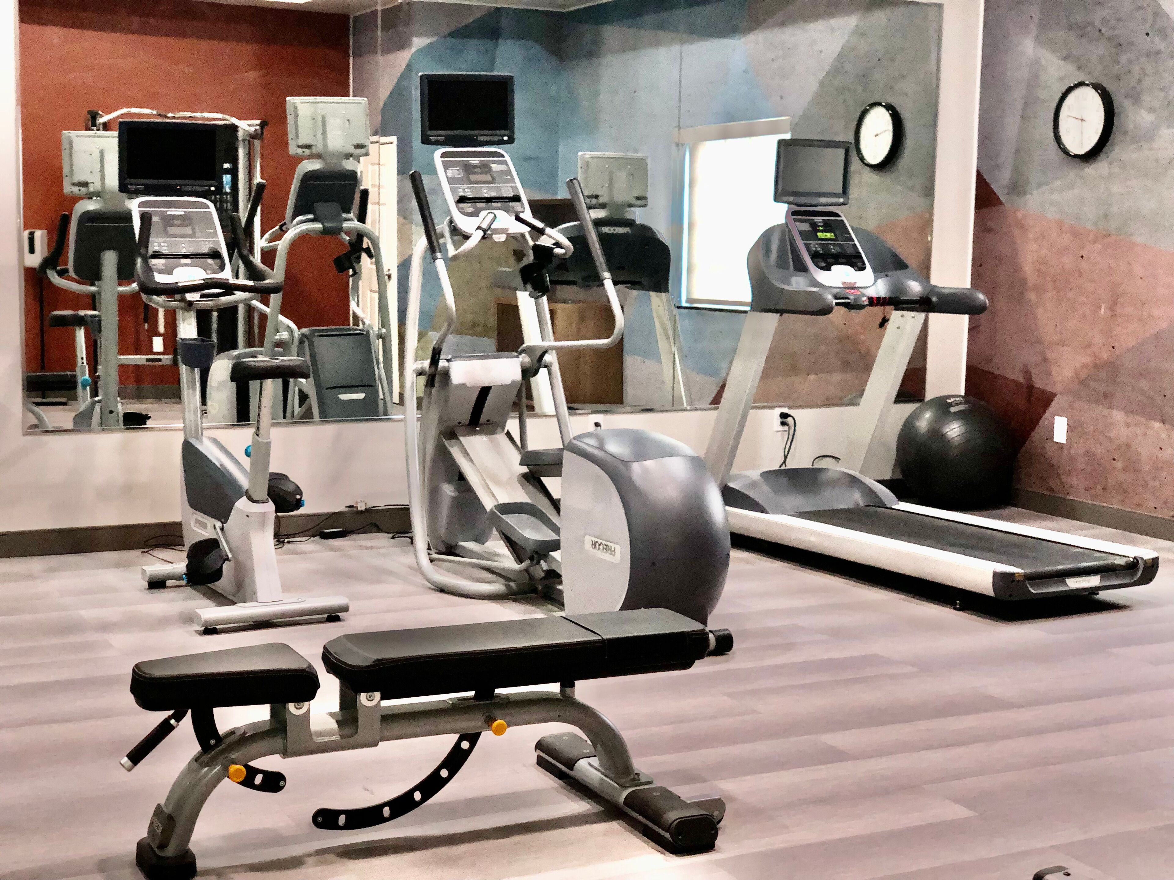 A gym with various exercise equipment including treadmills, elliptical machines, and weight benches.