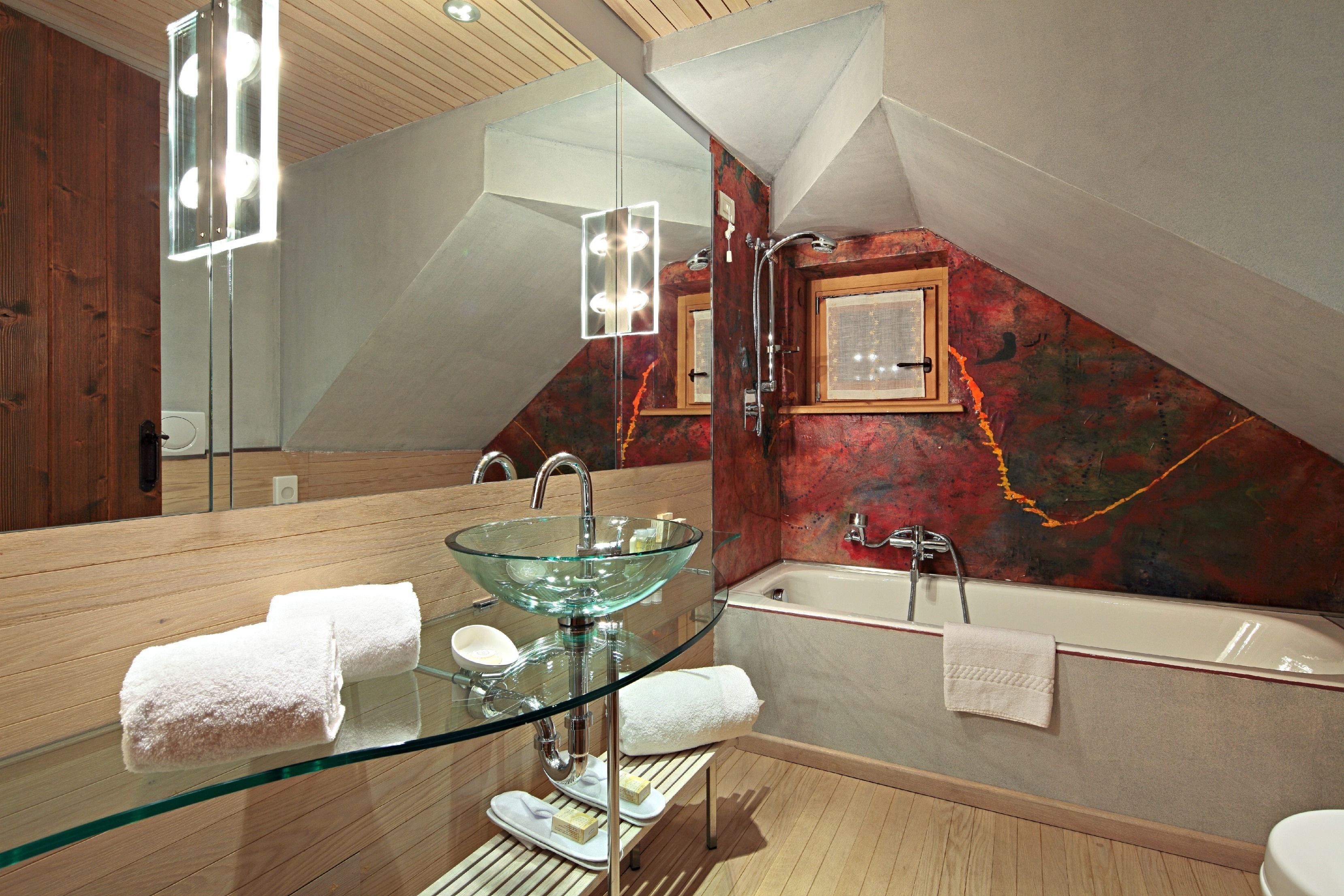 Un bagno moderno con un lavandino in vetro, una vasca da bagno e uno specchio grande.