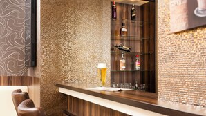 Eine Bar mit einer Holztresen, Barhocker und Regalen mit Flaschen.