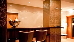 Ein modernes Badezimmer mit einem großen Spiegel, einer Duschkabine und einer Bar mit zwei Hockstühlen.