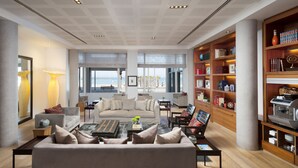 A spacious living room with a large sofa, coffee table, and bookshelves filled with books and decorative items. - Sea Executive Suites (Tel Aviv)