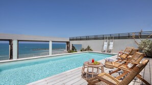A poolside area with a view of the ocean, wooden deck, and lounge chairs. - Sea Executive Suites (Tel Aviv)