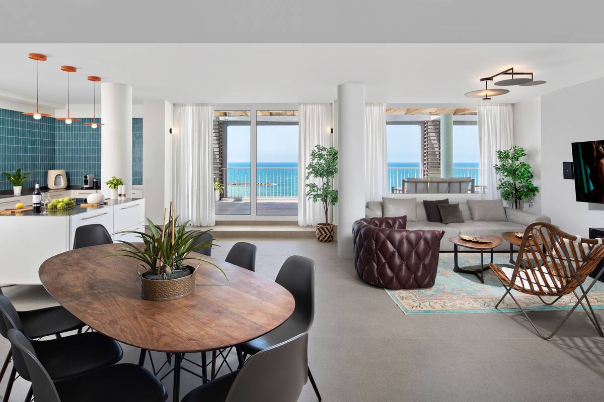A modern apartment with a kitchen, dining area, living room, and balcony with ocean views.
